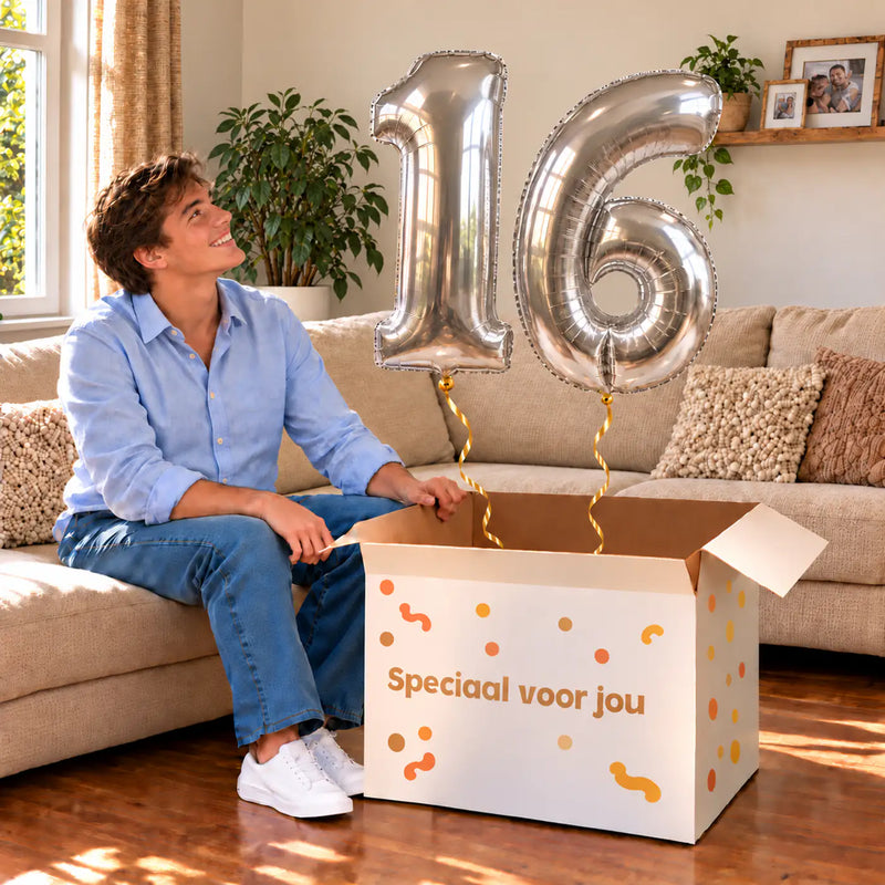 16 Jaar Cijfer Ballonnen Zilver met twee heliumgevulde cijferballonnen en een jarige in een warme woonkamer