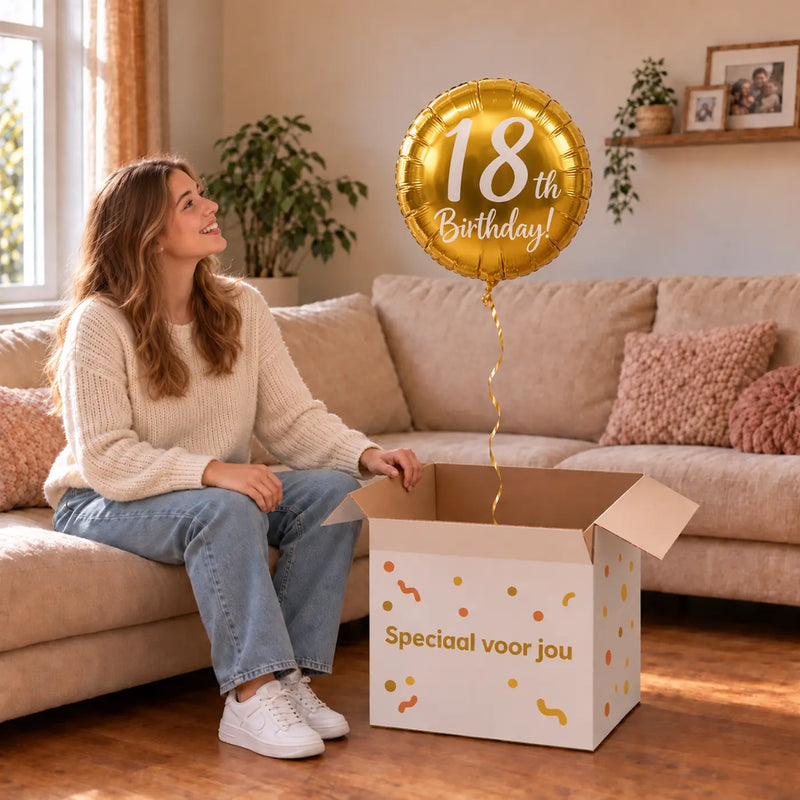 Vrouw viert 18 jaar met 18th Birthday Helium Ballon Goud uit een cadeaudoos van Ballonnenshop.nl
