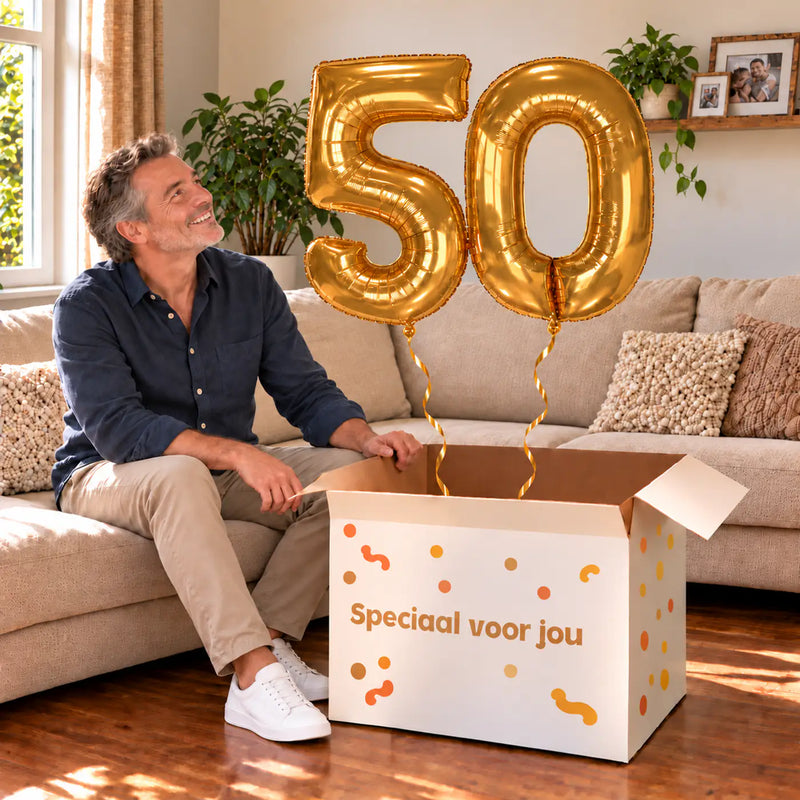 50 Jaar Cijfer Ballonnen Goud met twee heliumgevulde cijferballonnen en een jarige in een warme woonkamer