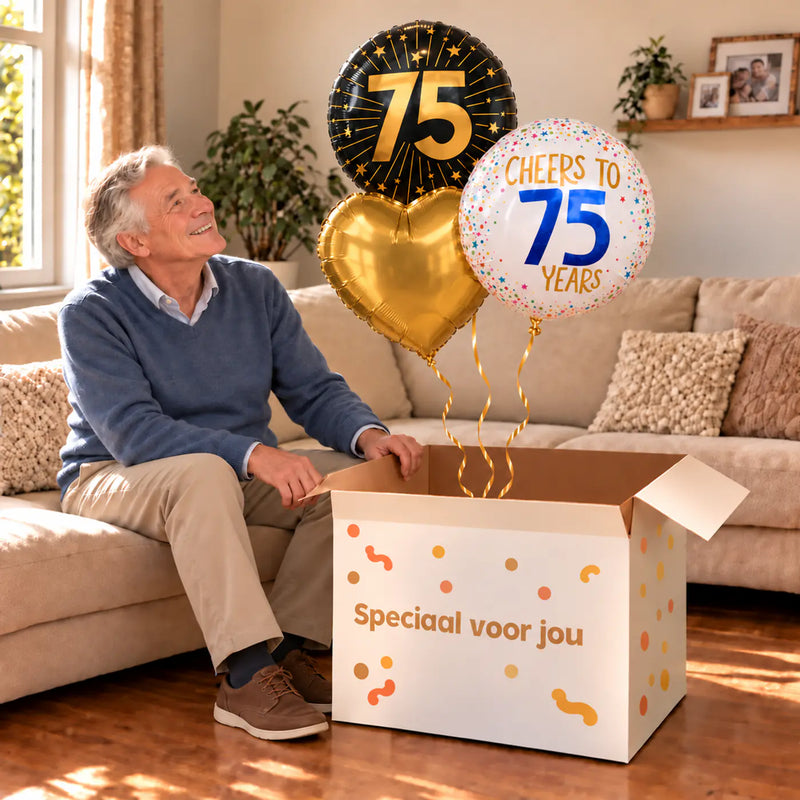 Een jarige met 75 Jaar Trosje Goud/Zwart/Wit boven een open Speciaal voor jou-doos in een warme woonkamer.