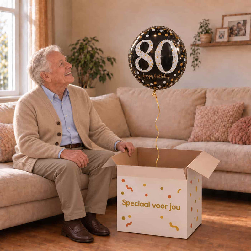 Man van 80 jaar pakt een zwarte, zilveren en gouden 80-jaarheliumballon uit een feestelijke doos.