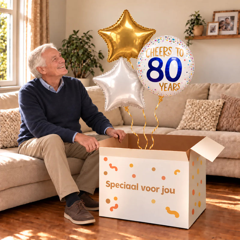Een jarige met 80 Jaar Trosje Wit/Goud/Blauw boven een open Speciaal voor jou-doos in een warme woonkamer.