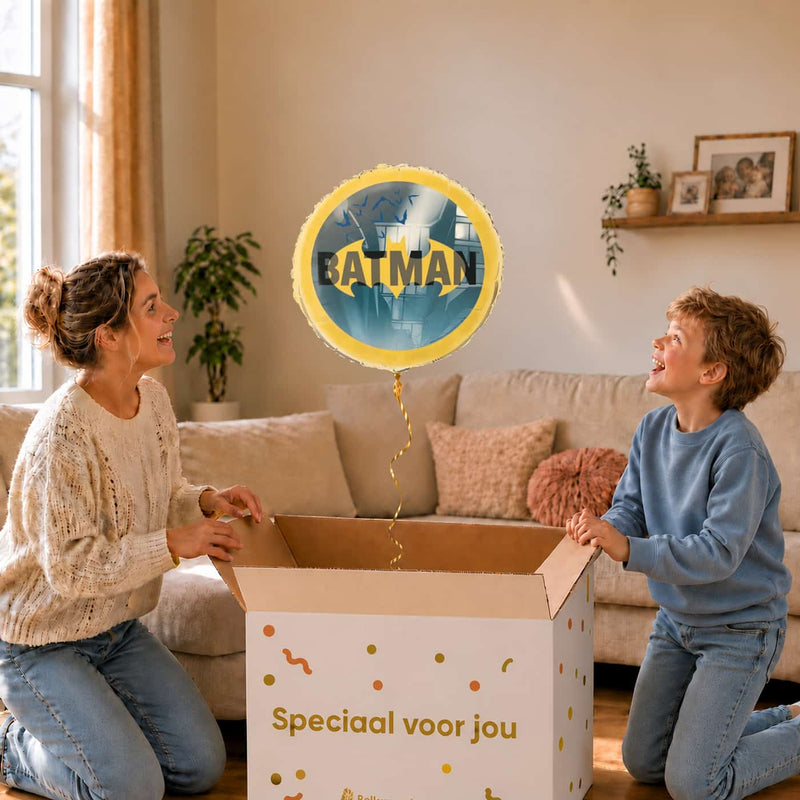 Moeder en jongen bekijken de ballon Batman Helium Ballon in zacht warm licht boven de geopende cadeaudoos ‘Speciaal voor jou’.