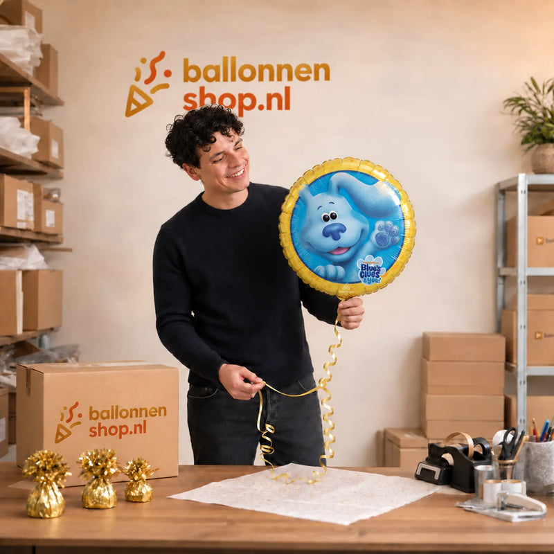 Jesse houdt de Blue's Clues Helium Ballon vast in de warme werkplaats van Ballonnenshop.nl.