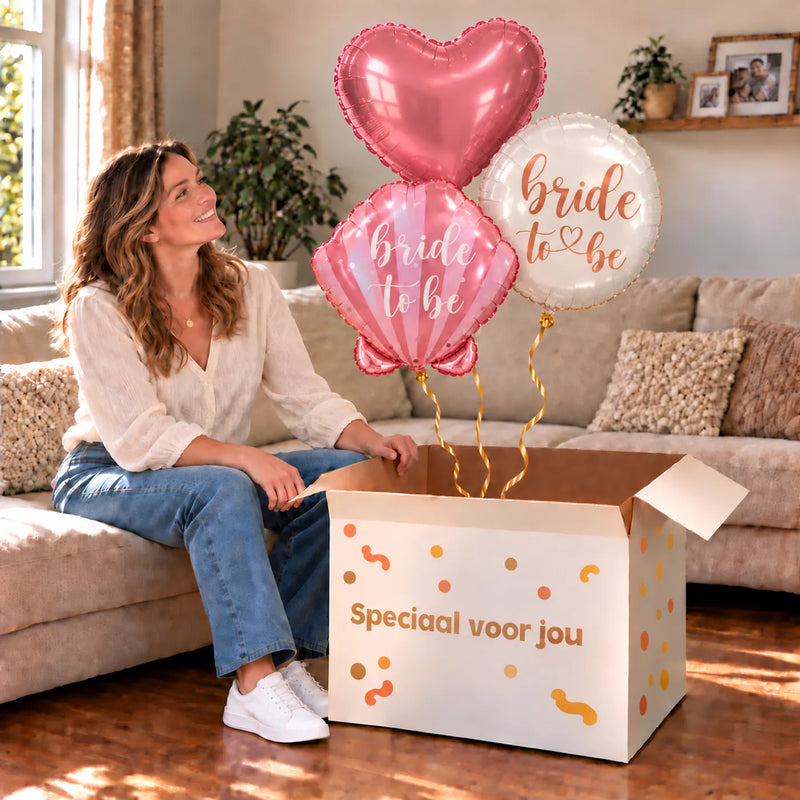 Een feestelijk huwelijksmoment met Bride To Be Trosje Ballonnen boven een open Speciaal voor jou-doos in een warme woonkamer.