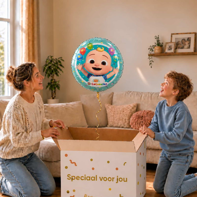Moeder en jongen bekijken een Cocomelon Baby-ballon van 46 cm met JJ boven een geopende cadeaudoos.