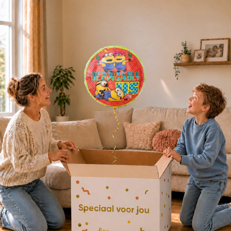 Moeder en jongen bekijken de ballon Despicably Us Minion Ballon in zacht warm licht boven de geopende cadeaudoos ‘Speciaal voor jou’.