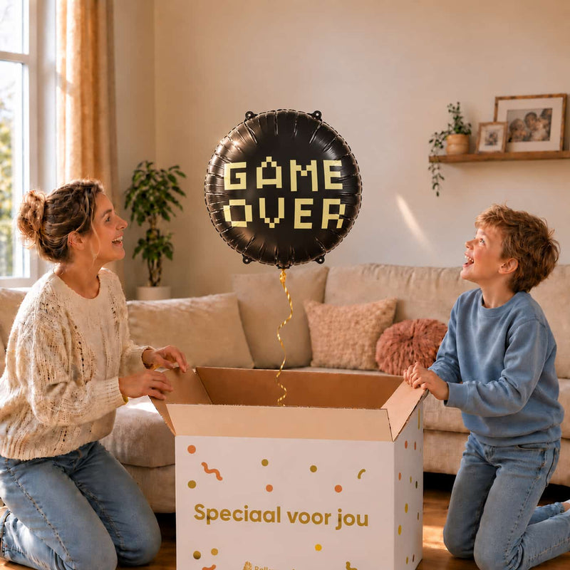 Moeder en jongen pakken een zwarte Game Over heliumballon van 45 cm met pixelletters uit de cadeaudoos.
