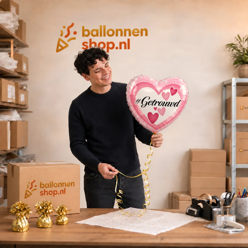 Jesse houdt de Getrouwd Helium Ballon vast in de warme werkplaats van Ballonnenshop.nl.