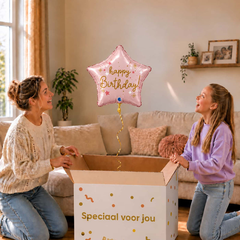 Meisje en moeder kijken naar een lichtroze Happy Birthday sterballon van 45 cm boven de cadeaudoos.
