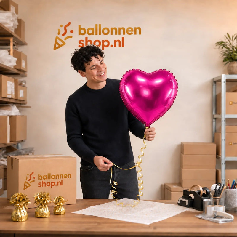 Jesse houdt de Hart Ballon Fuchsia vast in de warme werkplaats van Ballonnenshop.nl.