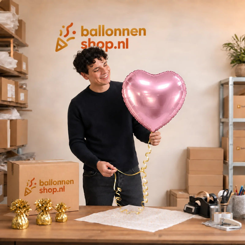 Jesse houdt de Hart Ballon Roze – 46 cm vast in de warme werkplaats van Ballonnenshop.nl.