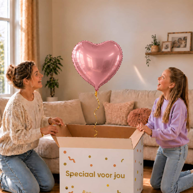 Roze hartjesballon van 46 cm zweeft boven een open cadeaudoos bij een moeder en meisje.