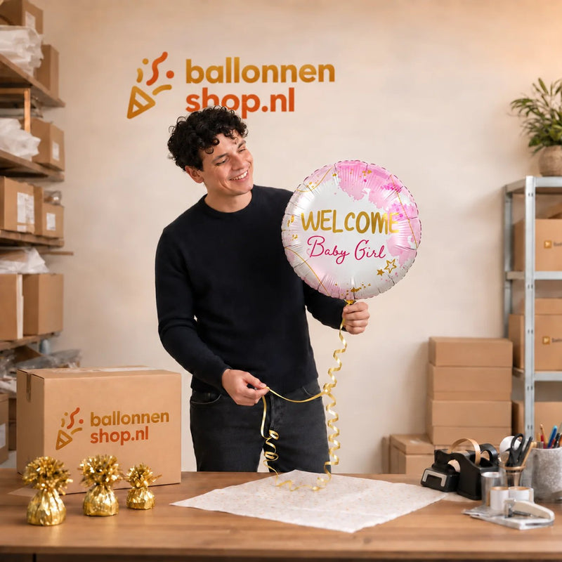 Jesse houdt de Helium Ballon Welcome Baby Girl vast in de warme werkplaats van Ballonnenshop.nl.