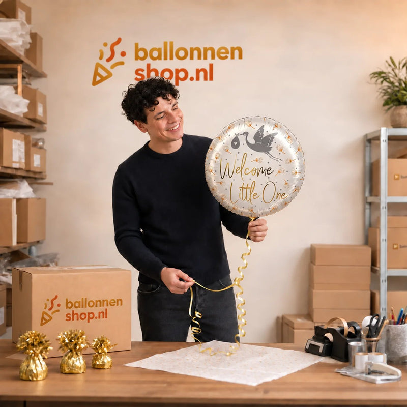 Jesse houdt de Helium Ballon Welcome Little One vast in de warme werkplaats van Ballonnenshop.nl.