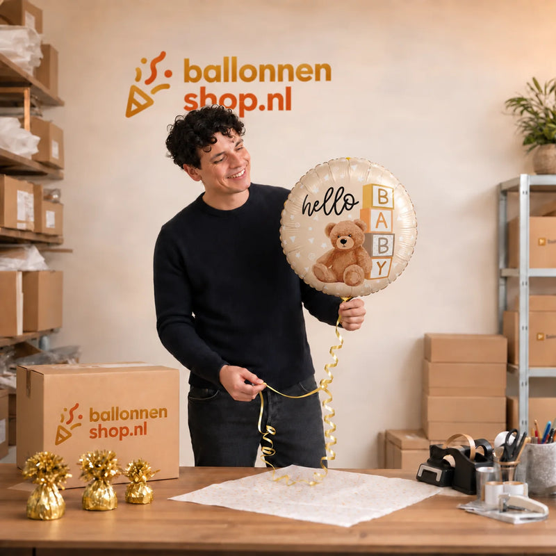 Jesse houdt de Hello Baby Teddy Bear Ballon vast in de warme werkplaats van Ballonnenshop.nl.
