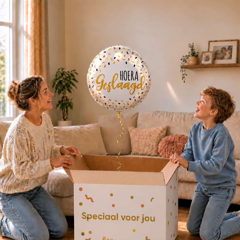 Moeder en jongen openen een cadeaudoos met een witte Hoera Geslaagd ballon van 46 cm met gouden letters.