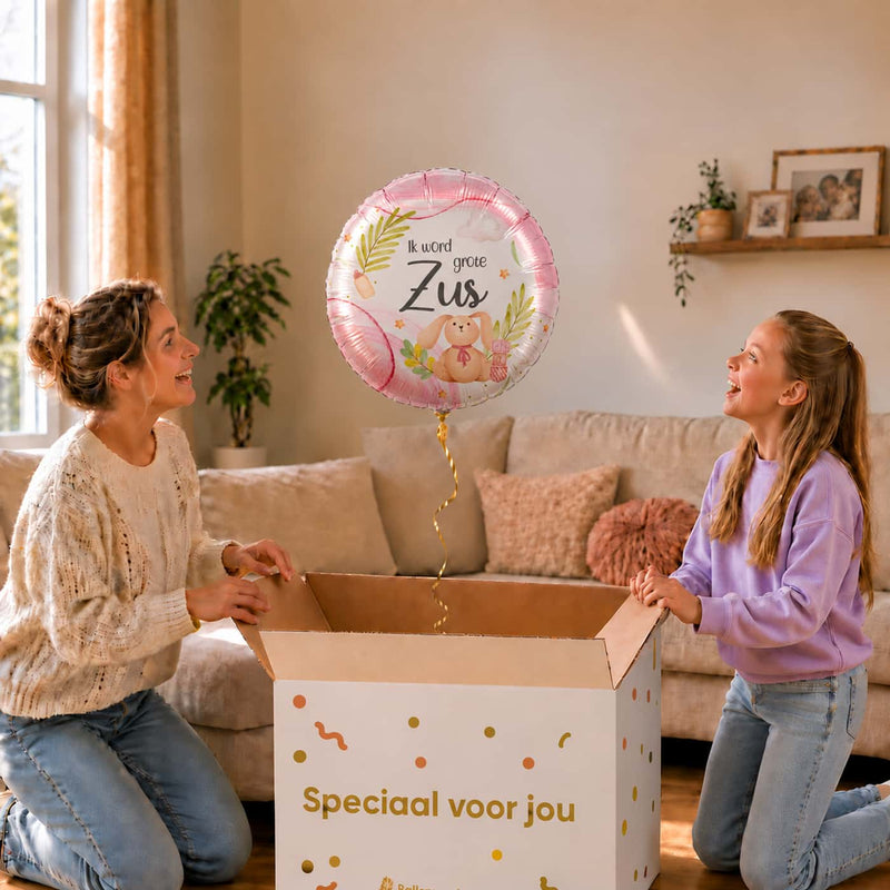 Moeder en dochter bekijken een roze Ik Word Grote Zus ballon van 46 cm met een konijntje boven de cadeaudoos.