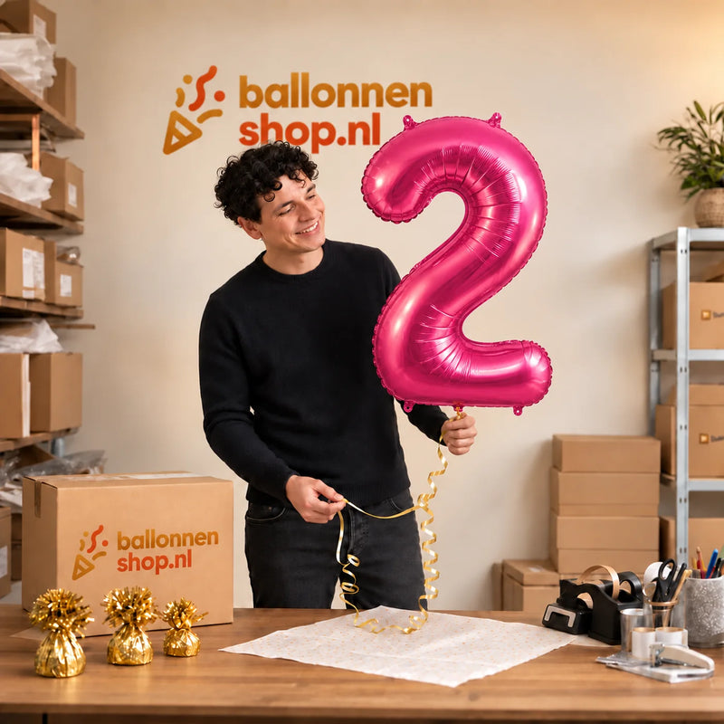 Jesse houdt de 2 Jaar Cijfer Roze XL Ballon vast in de warme inpakruimte van Ballonnenshop.nl.
