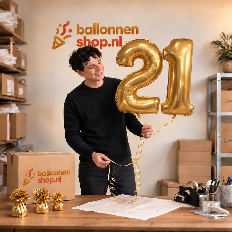 Jesse houdt de 21 Jaar Cijfer Ballonnen Goud vast in de warme inpakruimte van Ballonnenshop.nl.
