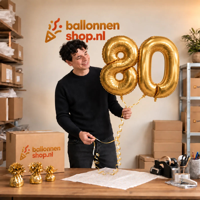 Jesse houdt de 80 Jaar Cijfer Ballonnen Goud vast in de warme inpakruimte van Ballonnenshop.nl.