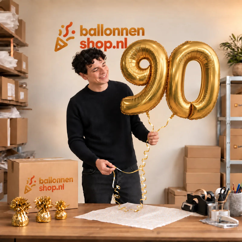 Jesse houdt de 90 Jaar Cijfer Ballonnen Goud vast in de warme inpakruimte van Ballonnenshop.nl.