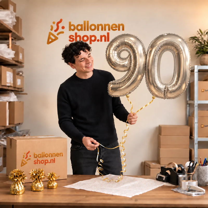 Jesse houdt de 90 Jaar Cijfer Ballonnen Zilver vast in de warme inpakruimte van Ballonnenshop.nl.