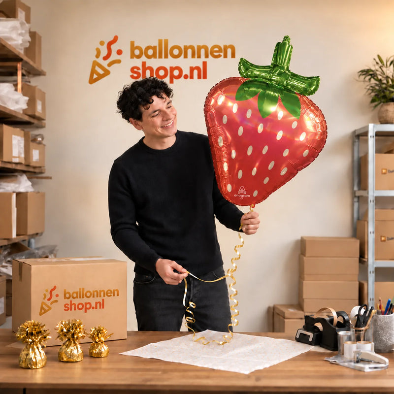 Jesse houdt de Aardbei Holographic Iridescent vast in de warme inpakruimte van Ballonnenshop.nl.