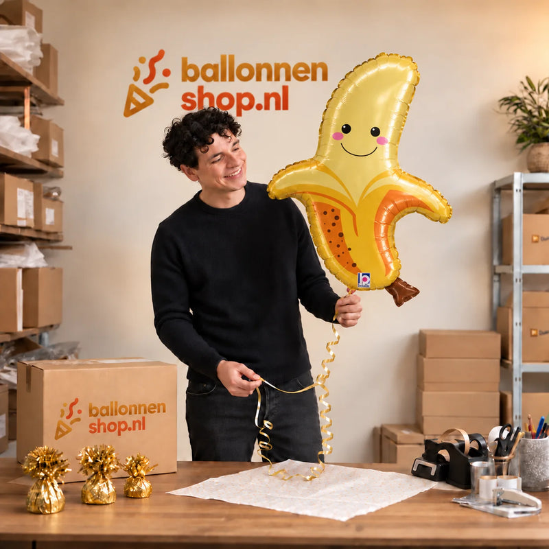 Jesse houdt de Banaan Helium XL Ballon vast in de warme inpakruimte van Ballonnenshop.nl.