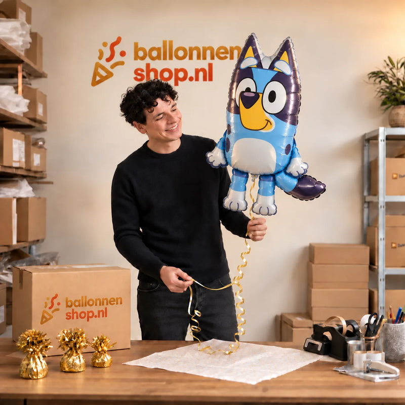 Jesse houdt de Bluey Helium XL Ballon vast in de warme inpakruimte van Ballonnenshop.nl.