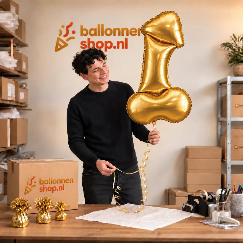 Jesse houdt de Gouden Piemel Helium XL Ballon vast in de warme inpakruimte van Ballonnenshop.nl.