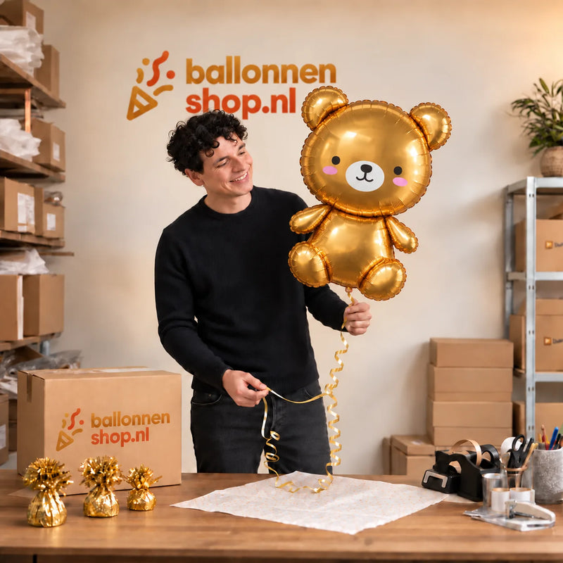 Jesse houdt de Gouden Teddybeer Helium XL Ballon vast in de warme inpakruimte van Ballonnenshop.nl.