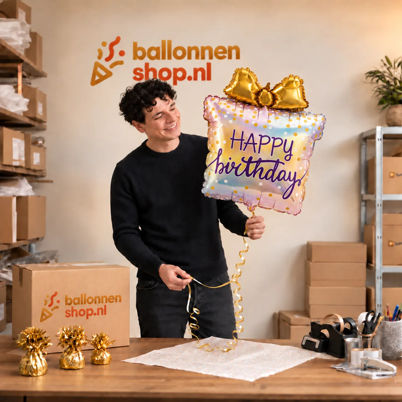 Jesse houdt de Happy Birthday Cadeau Regenboog vast in de warme inpakruimte van Ballonnenshop.nl.