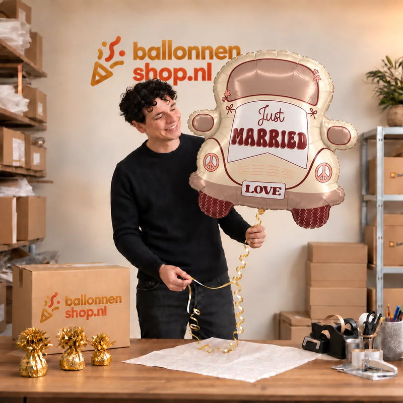 Jesse houdt de Just Married Auto XL Ballon vast in de warme inpakruimte van Ballonnenshop.nl.