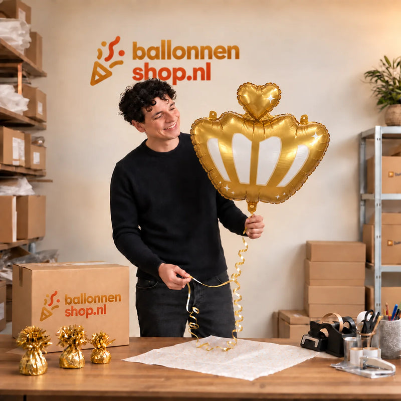 Jesse houdt de Kroon Helium Ballon vast in de warme inpakruimte van Ballonnenshop.nl.