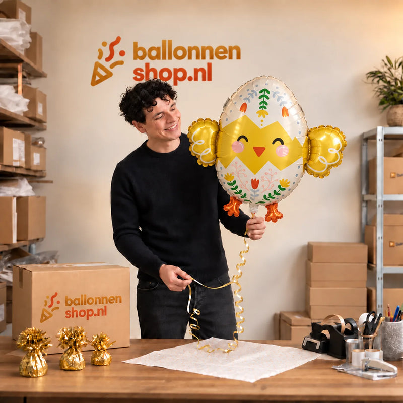 Jesse houdt de Kuiken Helium XL Ballon vast in de warme inpakruimte van Ballonnenshop.nl.