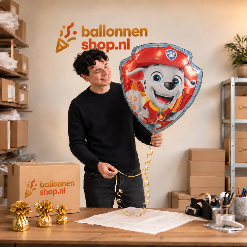 Jesse houdt de Marshall Paw Patrol XL Ballon vast in de warme inpakruimte van Ballonnenshop.nl.