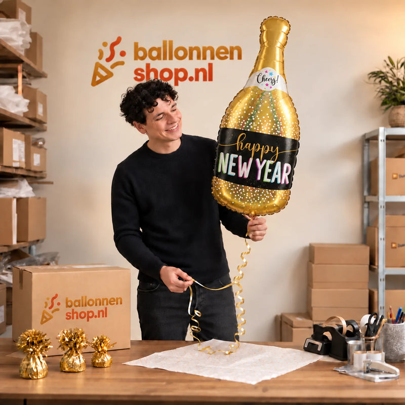 Jesse houdt de New Year Champagne XL Ballon vast in de warme inpakruimte van Ballonnenshop.nl.
