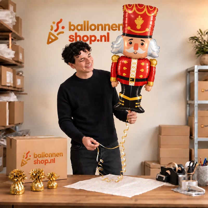 Jesse houdt de Notenkraker Kerst XL Ballon vast in de warme inpakruimte van Ballonnenshop.nl.