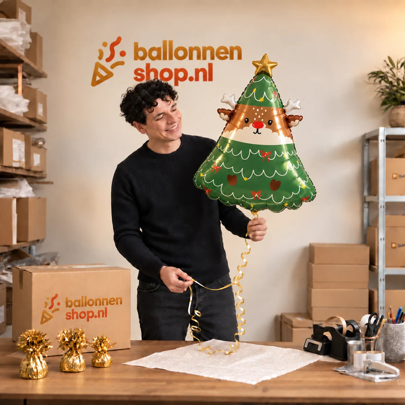 Jesse houdt de Rendier In Kerstboom Ballon vast in de warme inpakruimte van Ballonnenshop.nl.