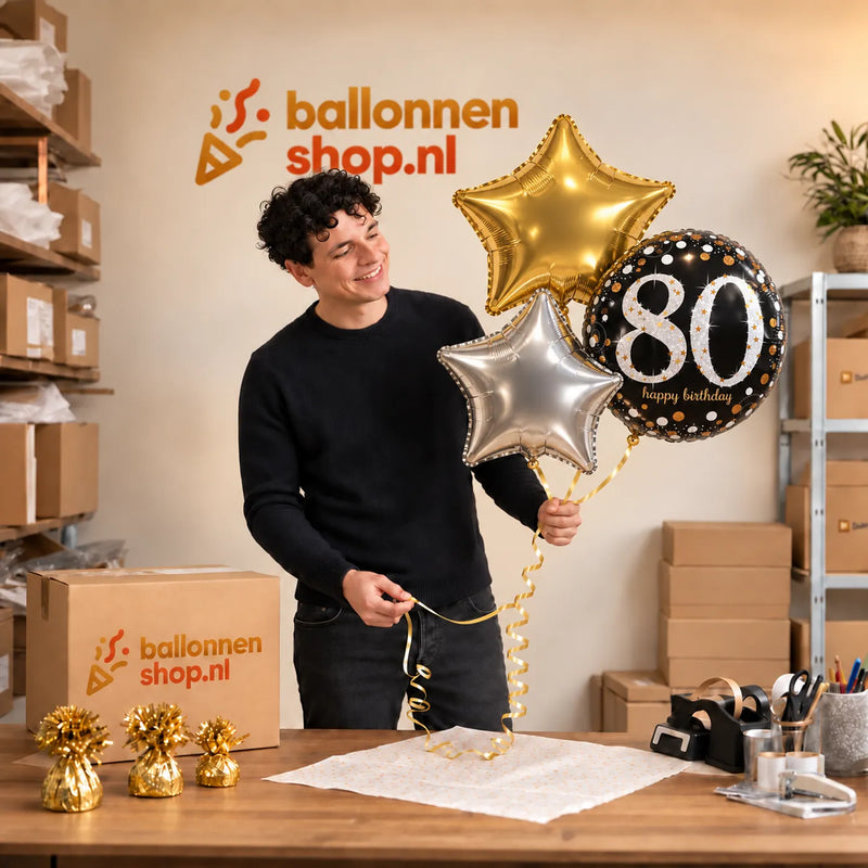 Jesse houdt 80 Jaar Trosje Zilver/Zwart/Goud vast in de warme werkplaats van Ballonnenshop.nl.