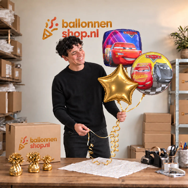 Jesse houdt Cars Trosje Goud/Blauw/Rood vast in de warme werkplaats van Ballonnenshop.nl.