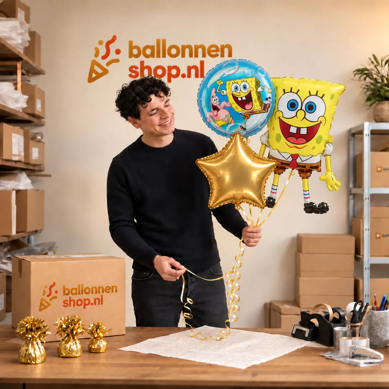 Jesse houdt Spongebob Trosje Goud/Blauw/Geel – 71 cm vast in de warme werkplaats van Ballonnenshop.nl.