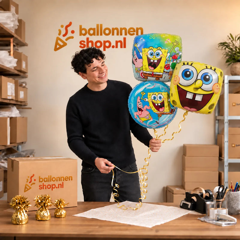 Jesse houdt Spongebob Trosje Blauw/Groen/Rood vast in de warme werkplaats van Ballonnenshop.nl.