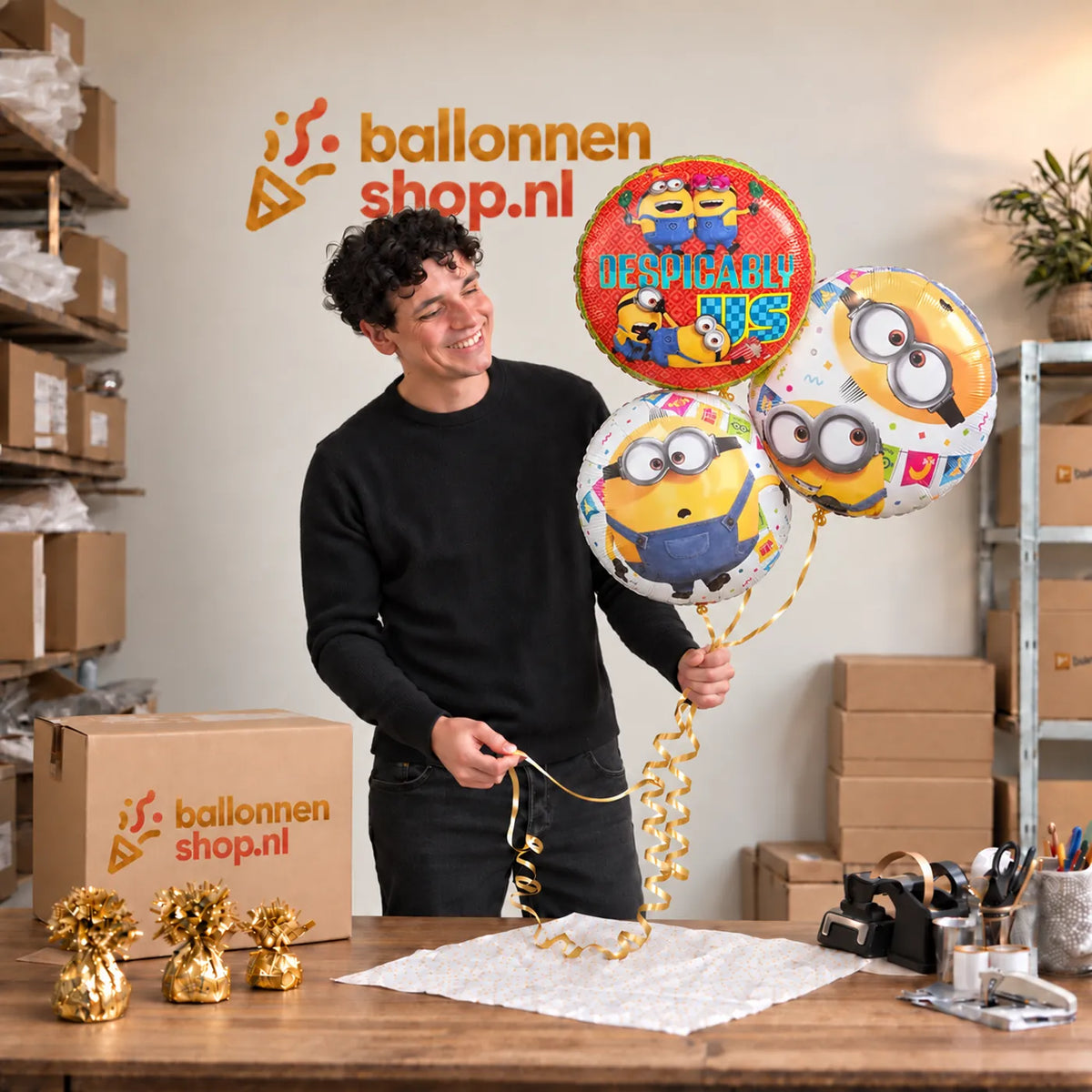 Jesse houdt Minion Trosje Geel/Wit/Rood – 46 cm vast in de warme werkplaats van Ballonnenshop.nl.