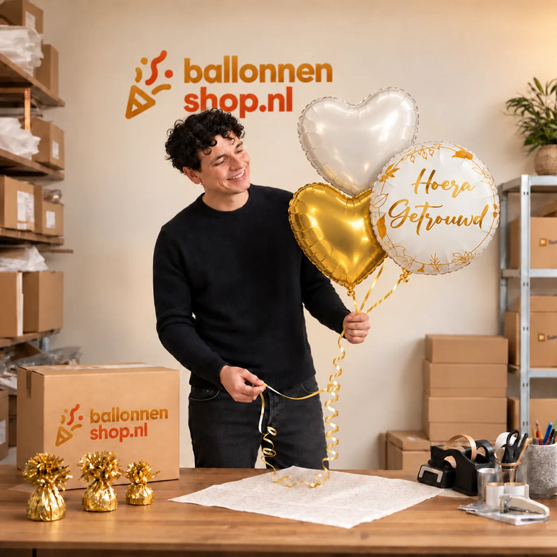 Jesse houdt Hoera Getrouwd Trosje Ballonnen vast in de warme werkplaats van Ballonnenshop.nl.