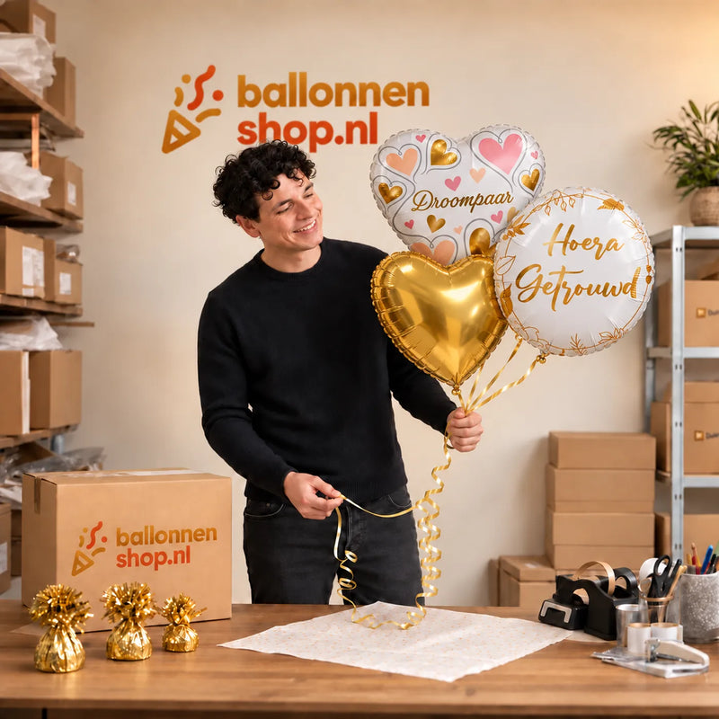 Jesse houdt Hoera Getrouwd Droompaar Trosje vast in de warme werkplaats van Ballonnenshop.nl.
