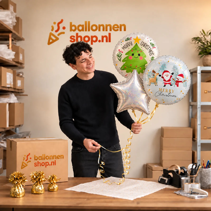 Jesse houdt Merry Christmas Trosje Ballonnen vast in de warme werkplaats van Ballonnenshop.nl.