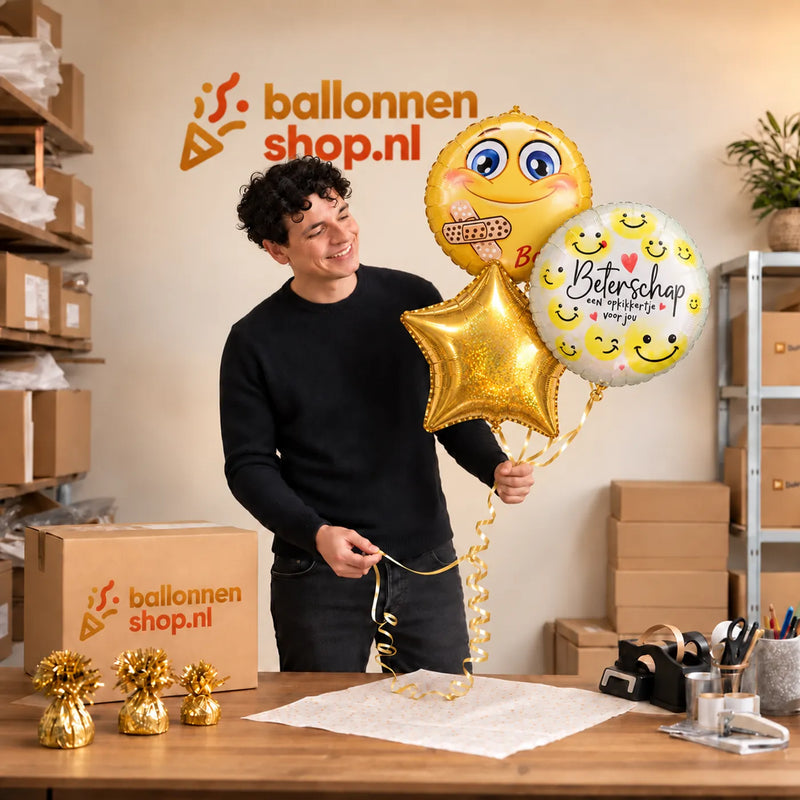 Jesse houdt Smiley Beterschap Trosje vast in de warme werkplaats van Ballonnenshop.nl.