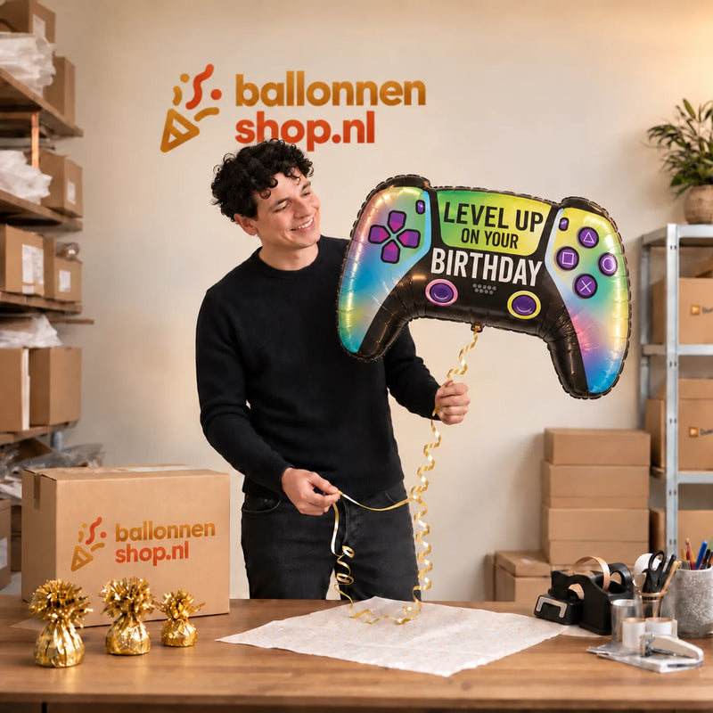 Jesse houdt de Vivid Game Controller Birthday XL vast in de warme inpakruimte van Ballonnenshop.nl.